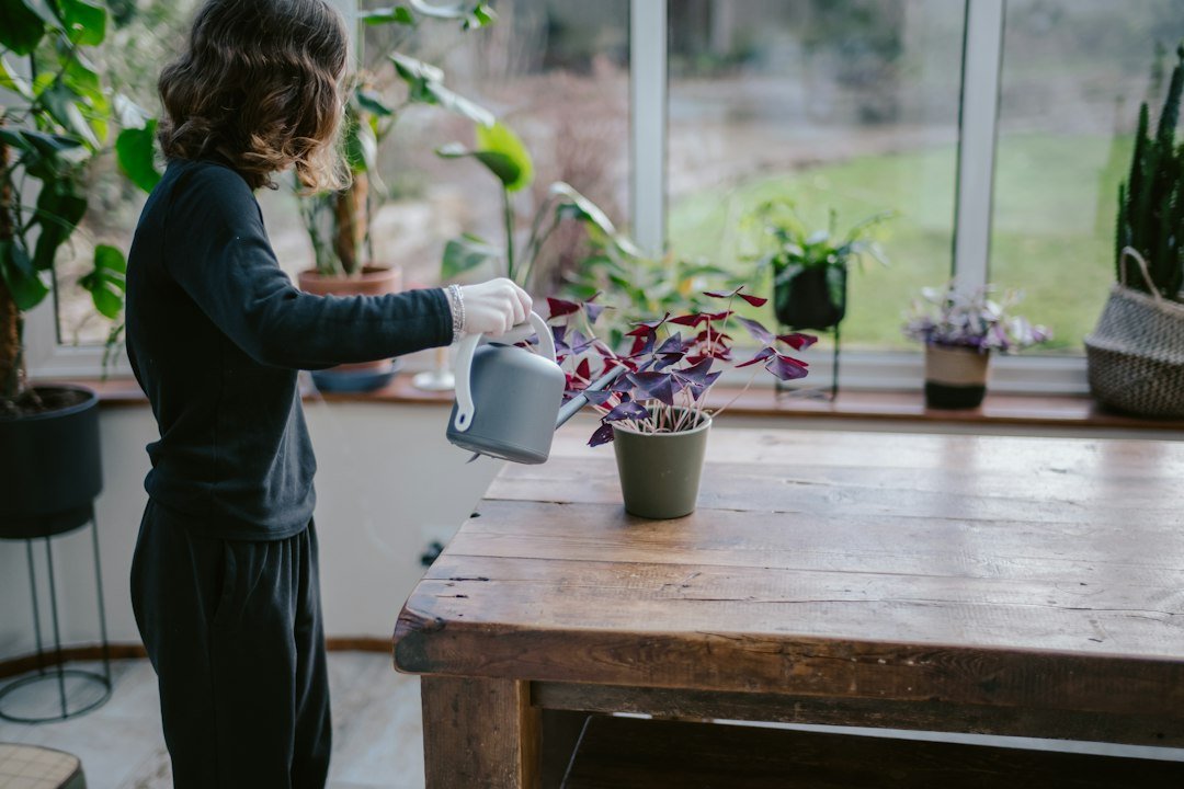 A woman checking and watering potted plants in a greenhouse